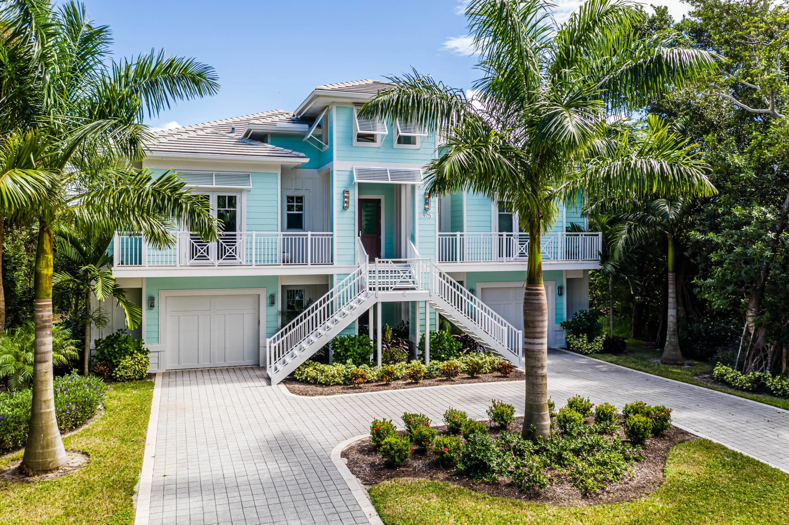 Single-story house with a two-car garage, neatly trimmed lawn, small palm trees, and a "For Rent" sign in the front yard beneath a clear blue sky—ideal for those seeking Homes for Rent in Naples.