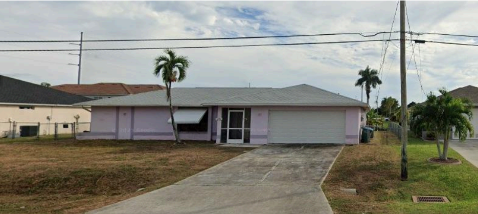 Single-story Jacaranda home with a gray roof, light pink walls, one-car garage, and concrete driveway. The 4 bedroom layout features two palm trees in the front yard and power lines overhead.